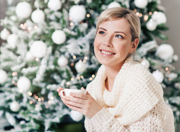 istock Young woman drinking tea by the Christmas tree 843308884