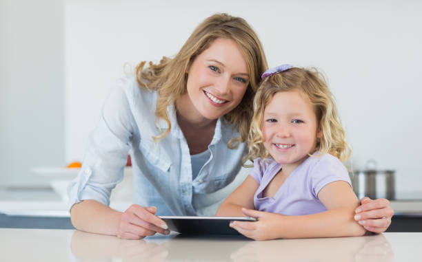 istock Mother and daughter holding digital tablet at table 843312604