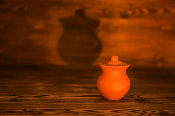 ceramic pot sealed with wax and mystical shadow on wooden background, close up
