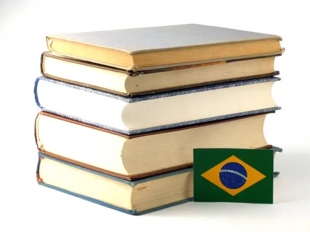 Brazilian flag with pile of books isolated on white background