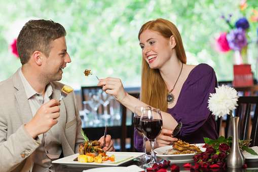 Happy young woman receives a gift from her partner. Romantic dinner setting with young couple dressed in evening wear
