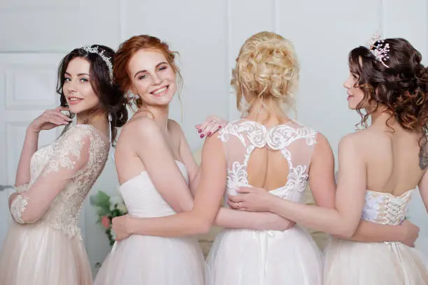 Bride in wedding salon. Four beautiful girl are in each other's arms. Close-up lace skirts