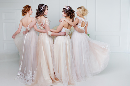 Bride in wedding salon. Four beautiful girl are in each other's arms. Close-up lace skirts