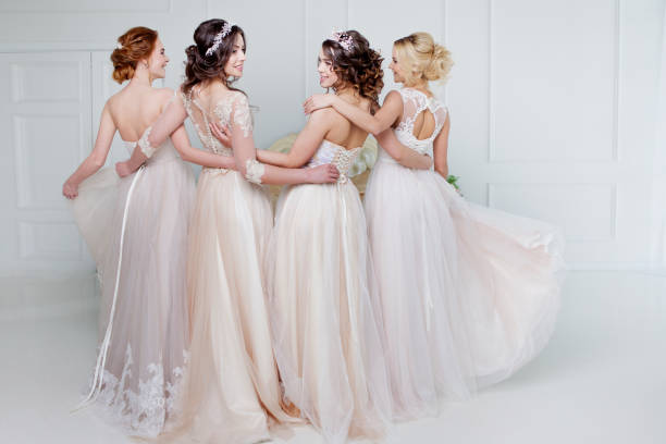 bride in wedding salon. four beautiful girl are in each other's arms. back, close-up lace skirts - hairstyle love wedding photography imagens e fotografias de stock