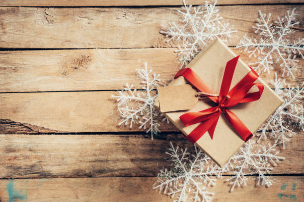 istock Christmas gift boxes placed and white snowflakes on wooden planks with space. 843342314