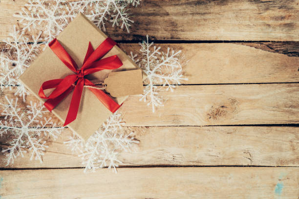 istock Christmas gift boxes placed and white snowflakes on wooden planks with space. 843342426