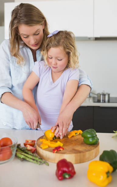 istock Mother assisting girl in chopping capsicum 843345496
