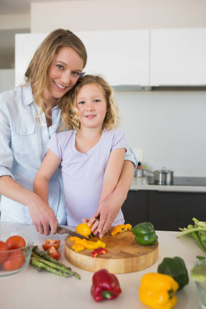 istock Mother assisting daughter in chopping capsicum 843345550