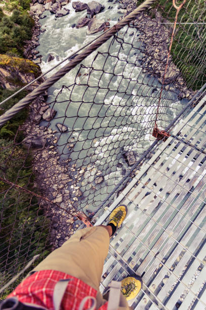 istock Backpacker crossing suspension bridge and looking down in Himalayas Nepal 843352774