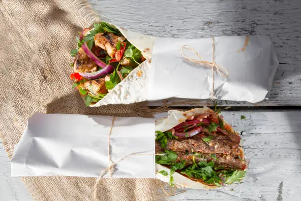 Healthy lunch snack. Tortilla wraps with grilled chicken fillet and fresh vegetables on white painted rustic wooden background. Top view.