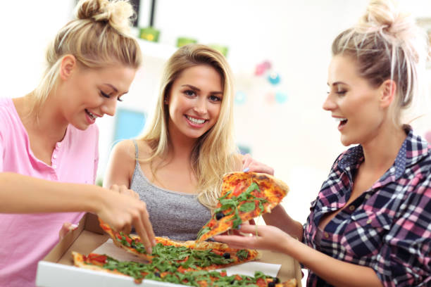 istock Three beautiful young women eating pizza at home 843364578