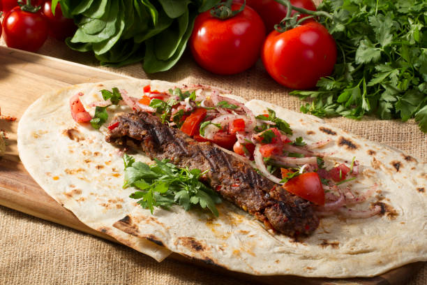 Turkish and Arabian Traditional Adana and Urfa kebab, minced meat kebab. Turkish food culture with salad on rustic wood textured background. Copy Space. stock photo