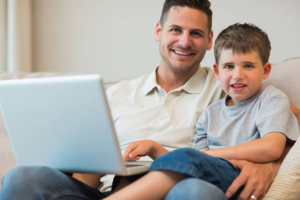istock Father and boy with laptop on sofa 843379268