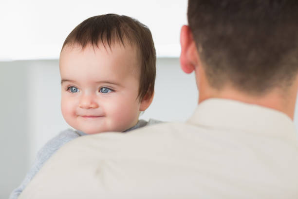 Cute baby boy being carried by father at home