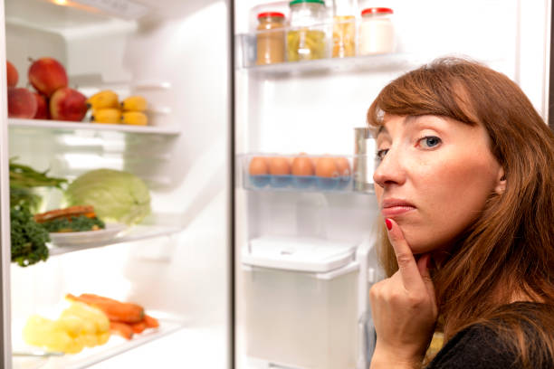 istock Confused young woman looking in fridge at kitchen 843386524