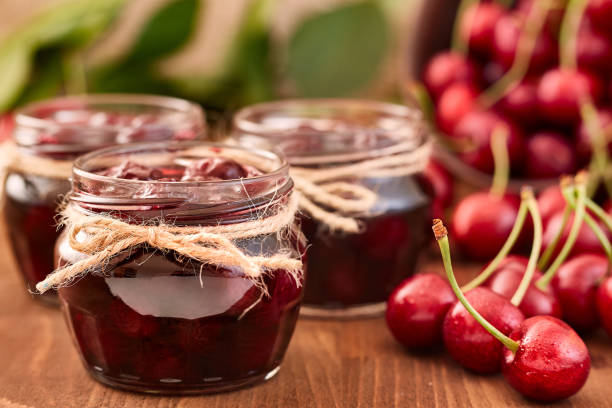 istock Cherry jam on wooden background in the jars 843394498