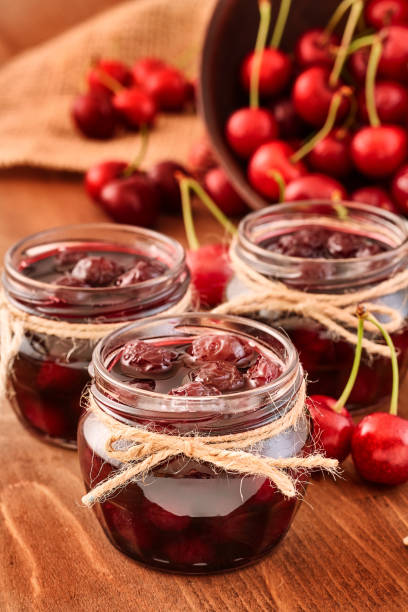 istock Cherry jam on wooden background in the jars 843394528