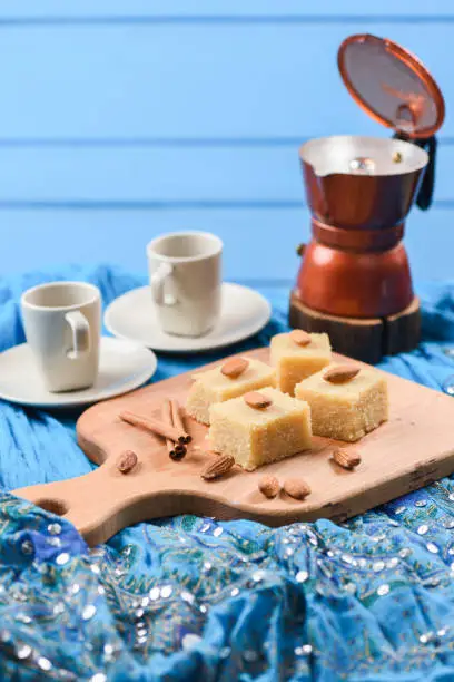 Homemade halava, traditional Indian sweetmeats served with coffee on bright blue embroidered cloth side view with copyspace