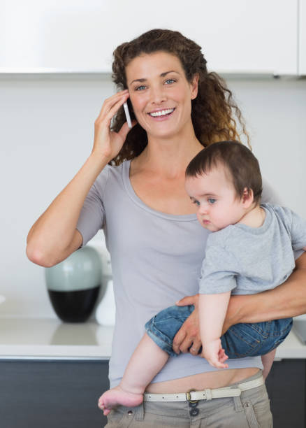 istock Happy woman answering smartphone while carrying baby 843414248
