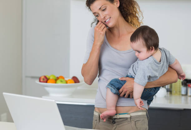 istock Mother answering cellphone while carrying baby 843414258