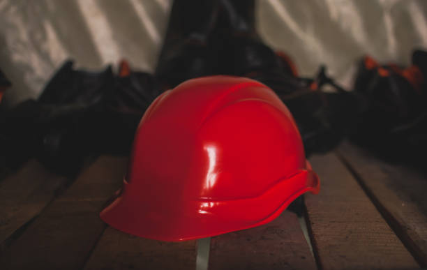 istock Red new protective helmet laying on wooden shelf in storage. 843415426