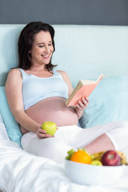 istock Pregnant woman eating and reading book 843425136