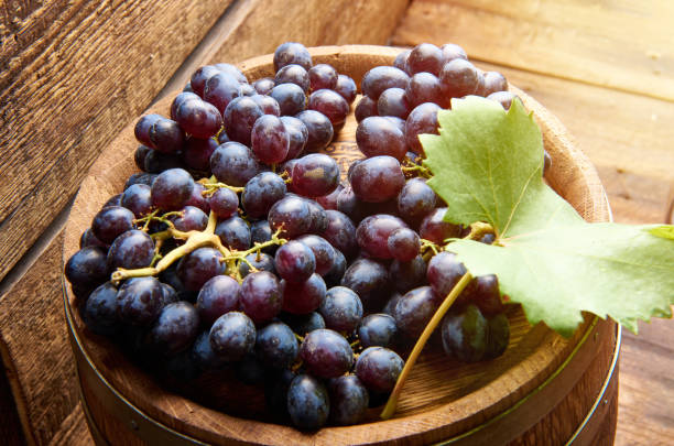istock Ripe dark grapes on the barrel with wine and green grape leaf. Top view. 843429010