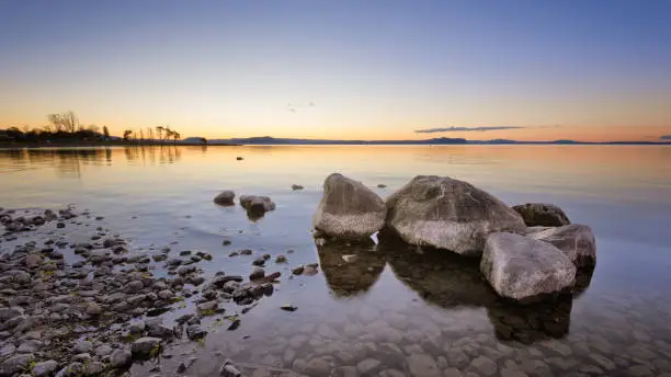 Rocks in the water on Lake Taupo, New Zealand during sunset.