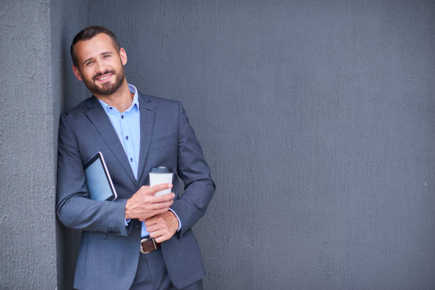 istock Young businessman in suit over grey wall background 843435704
