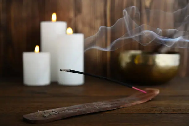 Indian incense stick with smoke on wooden background closeup