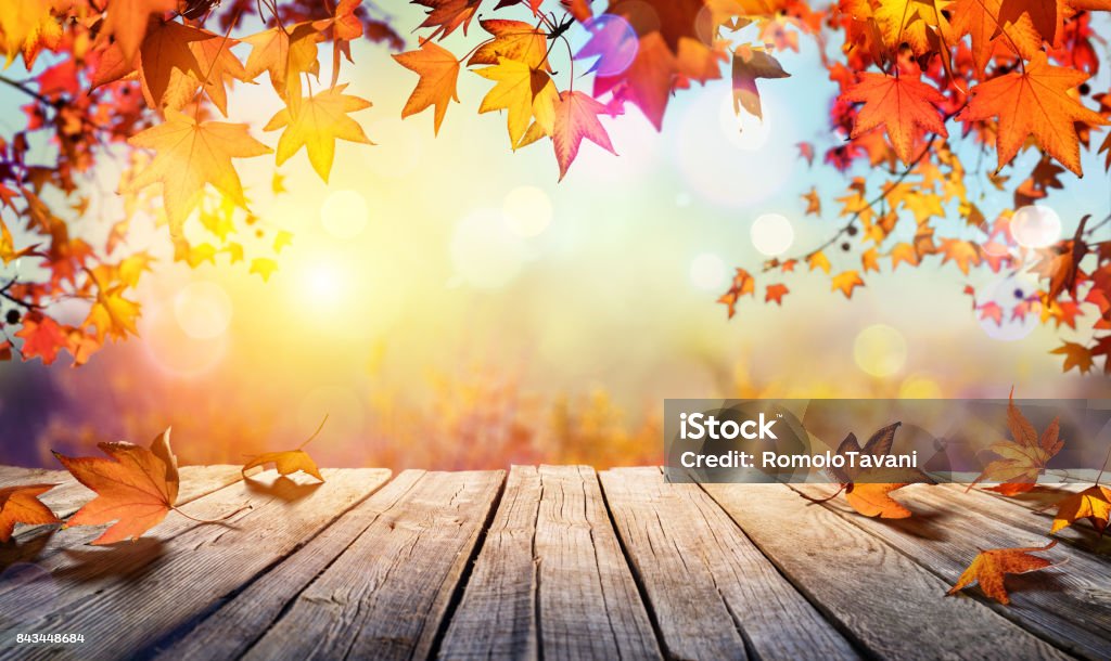 Mesa de madera con hojas de naranja y fondo borroso de otoño - Foto de stock de Otoño libre de derechos