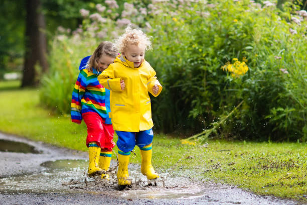 istock Kids play in rain and puddle in autumn 843452234