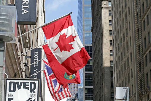 Toronto, Canada - August 19, 2017: Colorful flags of Canada, Ontario, Great Britain and USA over Yonge Street, Toronto. Background shows hotel and office buildings of the Church-Yonge Corridor and Downtown West neighbourhoods.