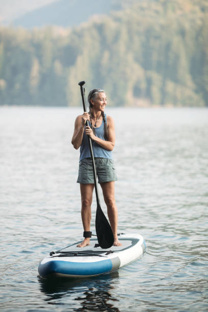 paddleboarding donna matura - paddleboard oar women lake foto e immagini stock