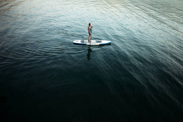 An active woman in her late 50's enjoys being out on her standup paddleboard (SUP) in the Pacific Northwest.  Shot in Washington State.