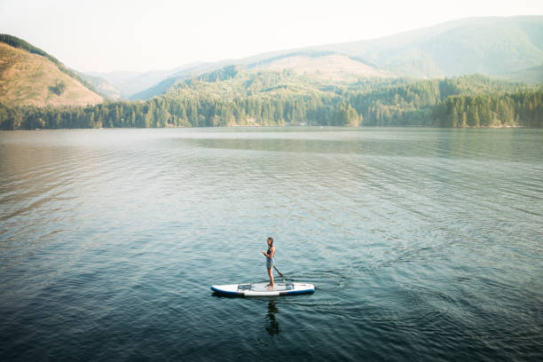 olgun kadın paddleboarding - paddle surfing stok fotoğraflar ve resimler