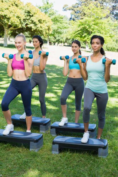 istock Sporty women doing step aerobics with dumbbells 843484514