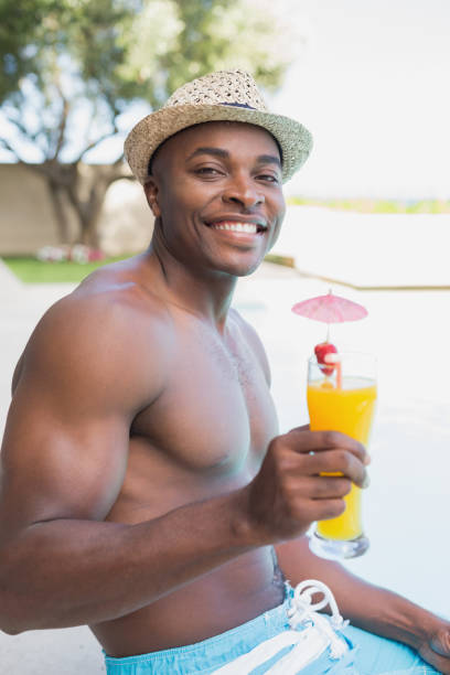guapo sin camisa con cóctel junto a la piscina - instructor one person fruit drinking fotografías e imágenes de stock
