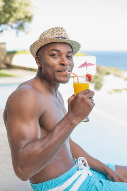 przystojny mężczyzna bez koszuli relaksujący się z koktajlem przy basenie - instructor one person fruit drinking zdjęcia i obrazy z banku zdjęć