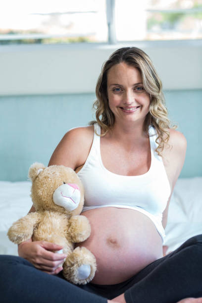 istock Pregnant woman sitting with a teddy bear 843494748