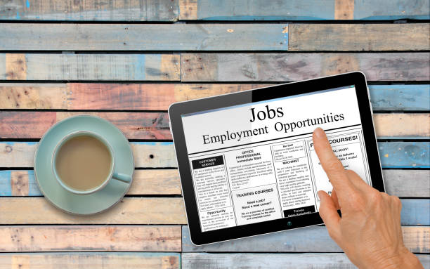 istock Online job hunting Hand with computer tablet reading employment ads on table with coffee 843510510