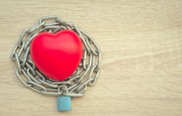 istock Padlock and chain locking a red heart on the wooden floor. 843513356