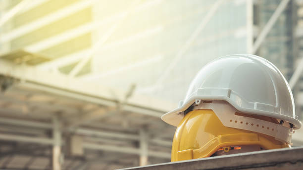 white, yellow hard safety helmet hat for safety project of workman as engineer or worker, on concrete floor on city stock photo