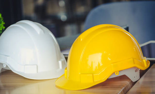 istock Hat engineers white and yellow on a wooden table. 843513410