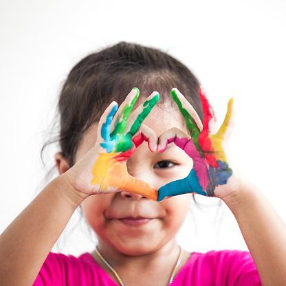 Cute asian child girl with hands painted make heart shape on white background