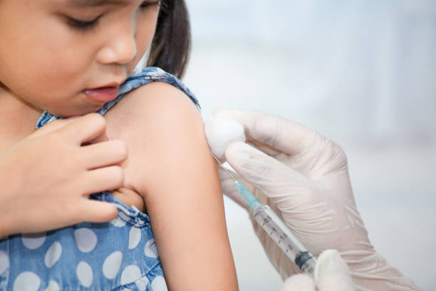 Doctor injecting vaccination in arm of asian little child girl stock photo