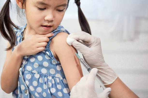 Doctor injecting vaccination in arm of asian little child girl stock photo