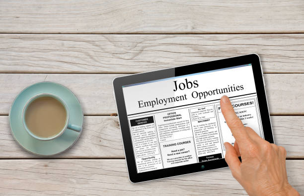 istock Online job hunting Hand with computer tablet reading employment ads on table with coffee 843521328