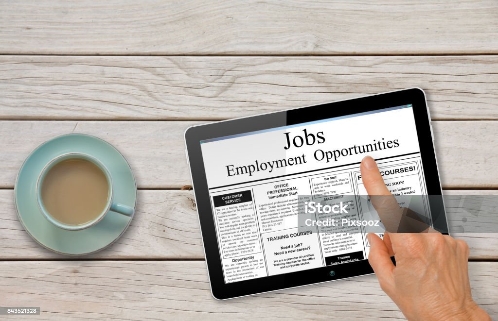 Online job hunting Hand with computer tablet reading employment ads on table with coffee Online job hunting Hand with computer tablet reading employment ads on table with coffee - recruitment concept Smart Card Stock Photo