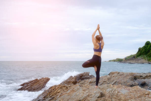 istock The woman practicing yoga on the beach at sunset. 843526090